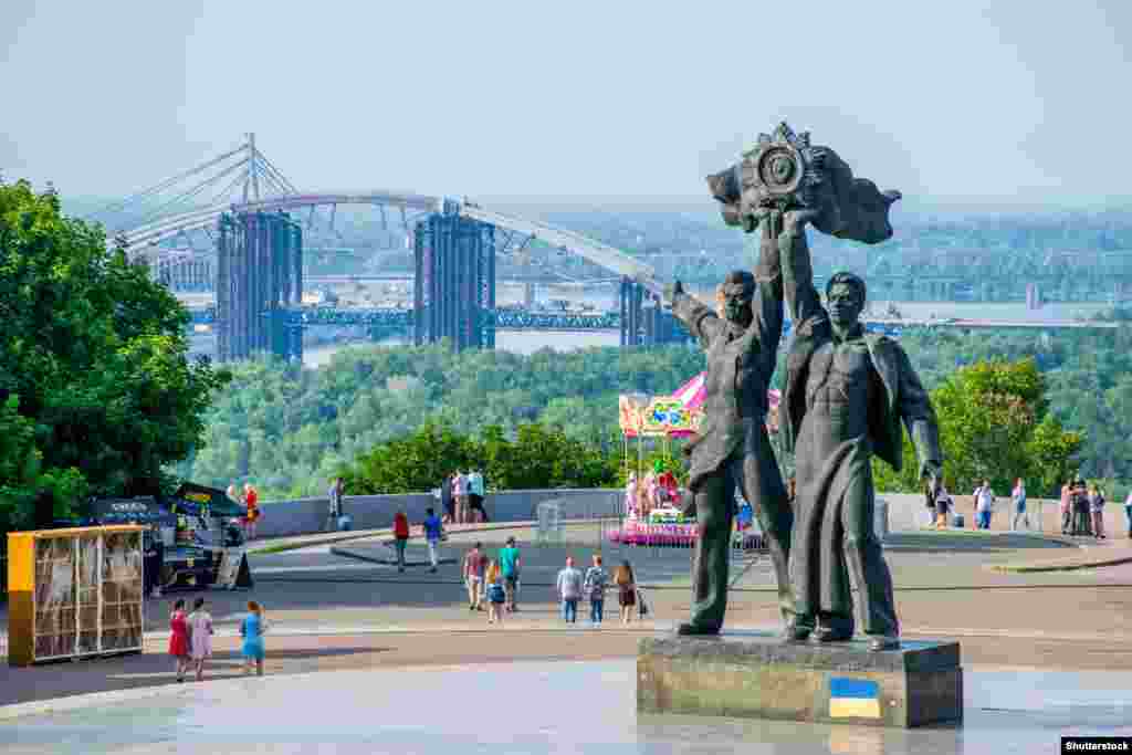 A June 2018 photo of the two main figures of a Soviet-era landmark originally called the Monument to Commemorate the Reunification of Ukraine with Russia in central Kyiv. The statues, representing a Russian and Ukrainian worker uniting under a Soviet state emblem, were cut down in April 2022. One month later, the monument complex, which is marked by a large titanium arch, was renamed the Arch of Freedom of the Ukrainian People. 