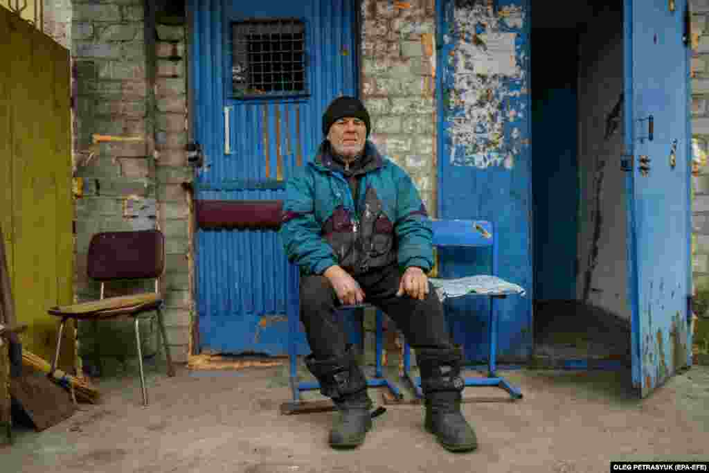Володимир седи до влезот на неговата станбена зграда, каде што тој и тројцата соседи живеат во подрумот. Времето го троши на сечење дрва што им се потребни на жителите за да се стоплат.