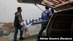 Rescue workers move one of two bodies of a couple who was killed by family members outside the hospital morgue in Karachi on November 27.