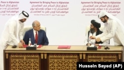 U.S. peace envoy Zalmay Khalilzad (left) and Mullah Abdul Ghani Baradar, the Taliban group's top political leader, sign a peace agreement between Taliban and U.S. officials in Doha on February 29.
