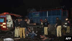 Pakistani policemen and volunteers move the bodies of victims at the site of a bomb explosion in Lahore on February 13. 