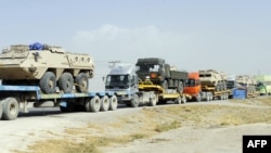 Pakistani drivers guide trailers carrying armored vehicles for NATO forces near Quetta. (file photo) 
