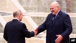 Belarusian leader Alyaksandr Lukashenka (right) greets Russian President Vladimir Putin in Minsk on November 23. The U.S. Treasury Department stated on December 5 that the Russian government and Belarus's regime "have been working together to coordinate and fund the movement of children from Ukraine to Belarus."