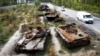 Cars pass by destroyed Russian tanks in a recent battle against Ukrainians in the village of Dmytrivka, close to Kyiv.